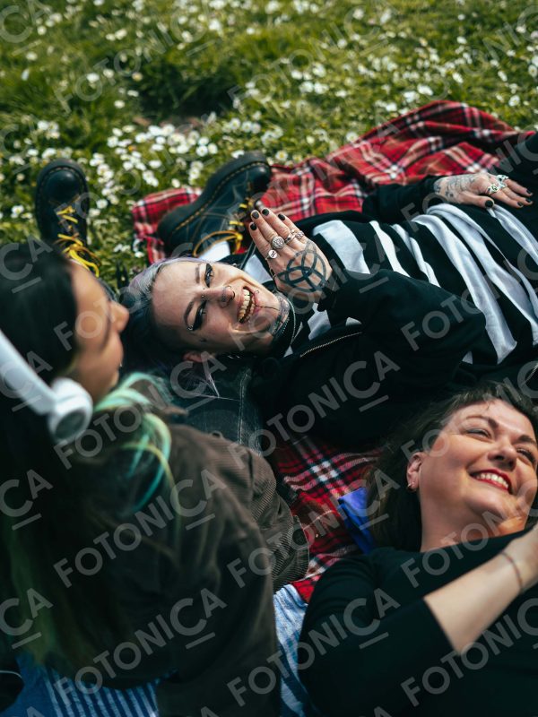 Persone su prato fiorito sorridono ascoltando musica